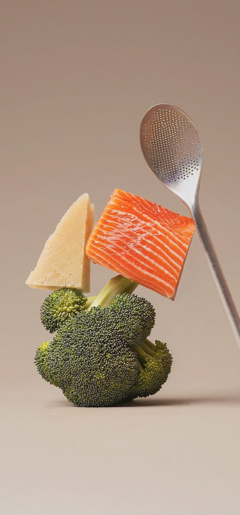 Salmon, cheese and broccoli balanced with a spoon